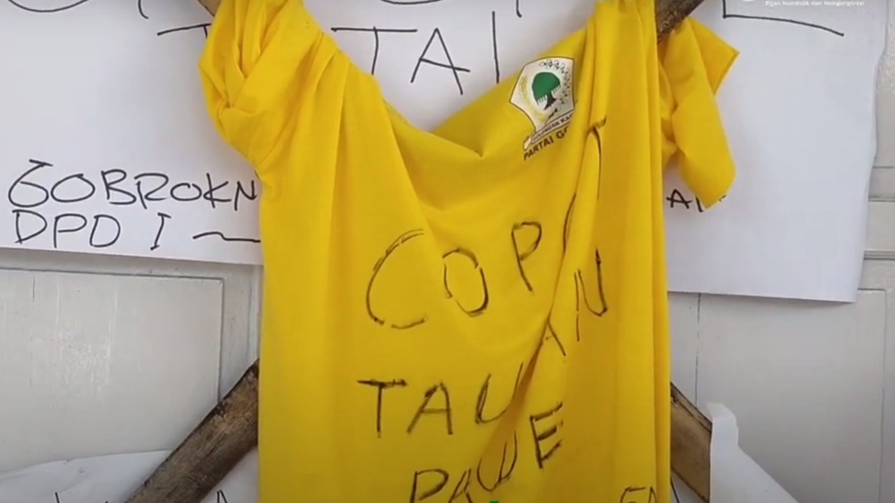 Tampak selembar baju berwarna kuning dengan logo Partai Golkar ditulisi copot Taufan Pawe, dipasang di pintu sekretariat DPD Golkar Bulukumba.